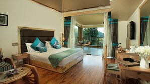 Ein Schlafzimmer mit Bett, Holzmöbeln, einem Schreibtisch und Blick ins Freie.