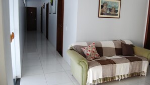 A hallway with a green sofa and a framed picture on the wall. - Pousada Santana (Trindade)
