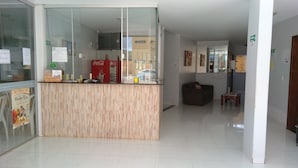 A reception area with a wooden counter, glass display cases, and a Coca-Cola refrigerator. - Pousada Santana (Trindade)