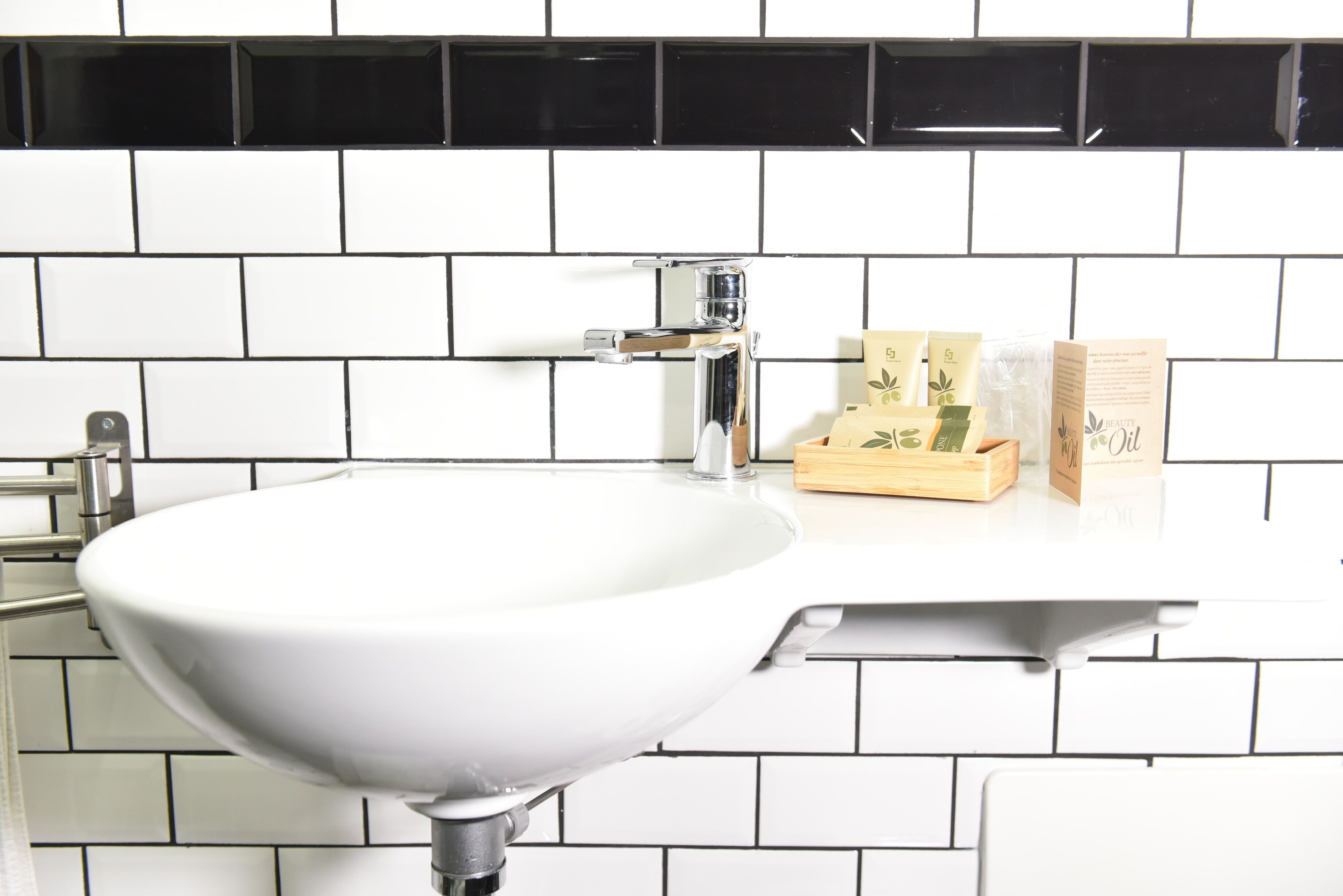 A bathroom with a white sink, black and white tiled backsplash, and a wooden box on the countertop.