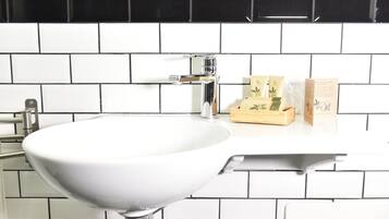 A bathroom with a white sink, black and white tiled backsplash, and a wooden box on the countertop.