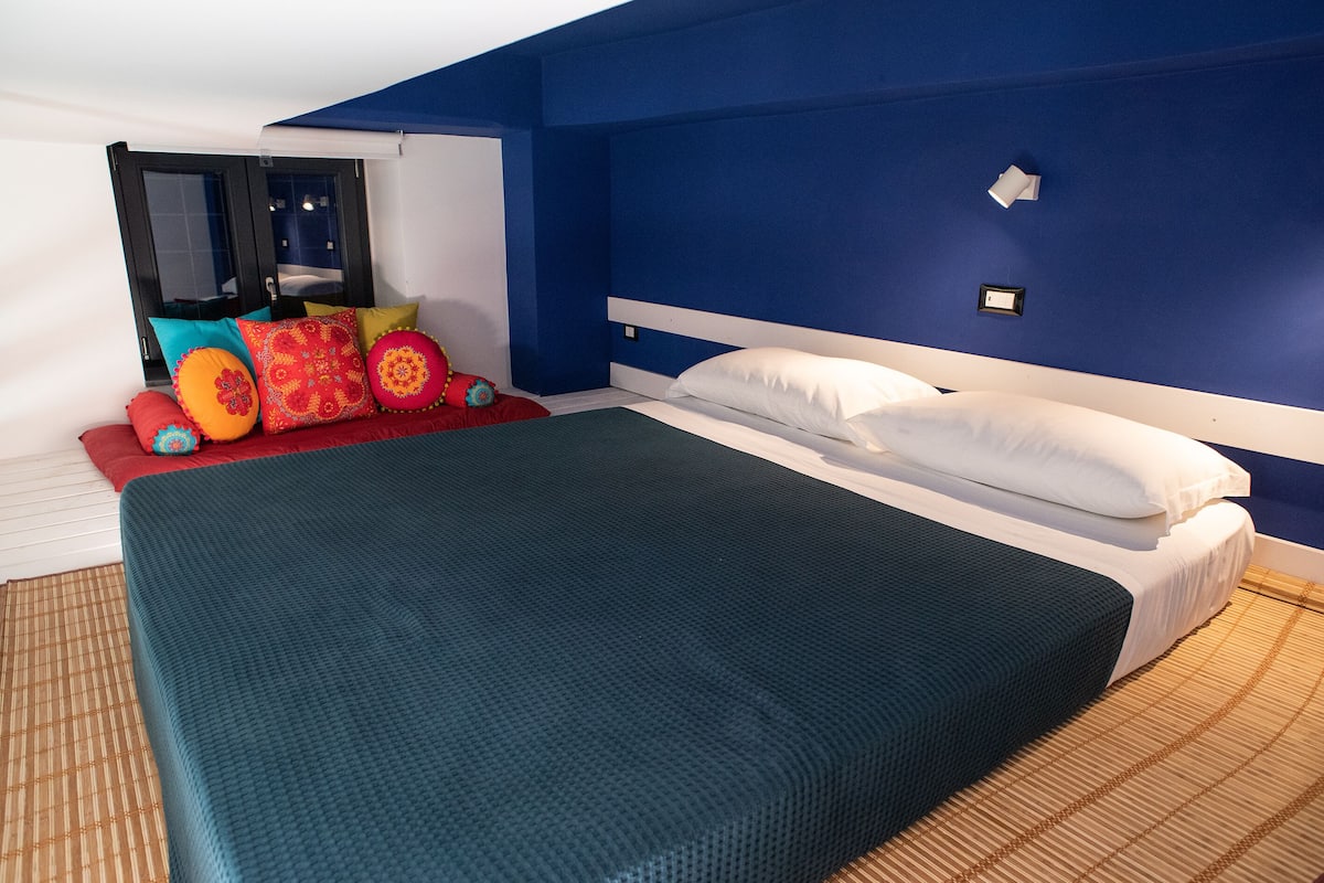 A bedroom with a bed, pillows, and a window.