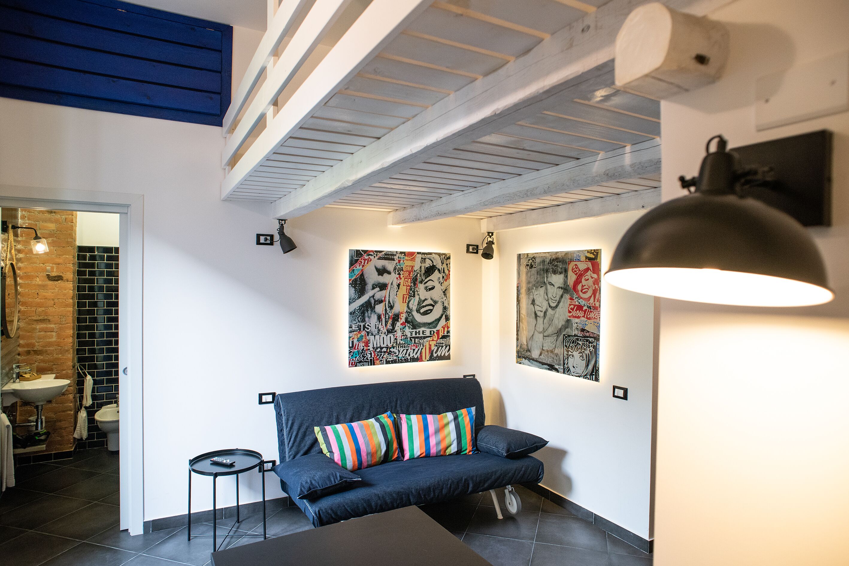 Un espacio habitable moderno con un sofá azul oscuro, almohadones a rayas coloridos y arte abstracto en la pared.