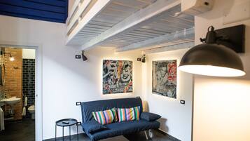 Un espacio habitable moderno con un sofá azul oscuro, almohadones a rayas coloridos y arte abstracto en la pared.