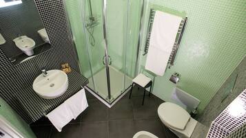 Une salle de bain avec une douche à parois de verre, un lavabo, des toilettes et un petit tabouret.