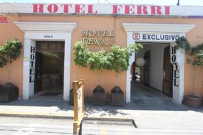 The exterior of Hotel Ferri, featuring its name and address, a sign indicating 'Exclusivo', and a row of potted plants in front. - Hotel Ferri (Oaxaca)