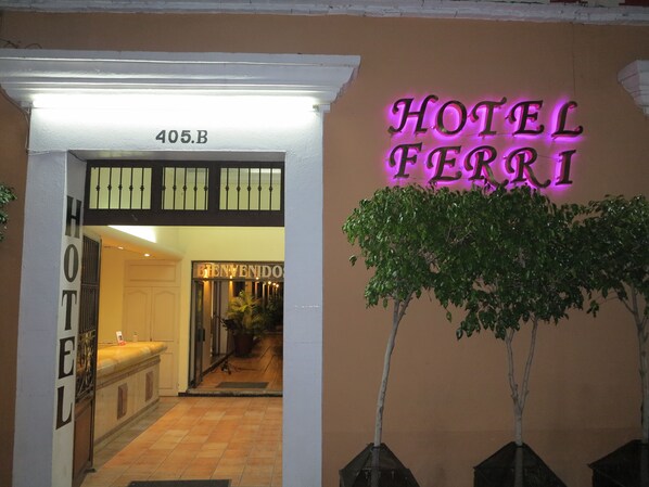 A hotel entrance with a neon sign reading "HOTEL FERRI" and a sign above the door that says "BIENVENIDOS". - Hotel Ferri (Oaxaca)