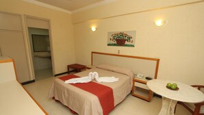 Una habitación de hotel con una cama, una mesita con manzanas, un cuadro en la pared y un televisor en un rincón.