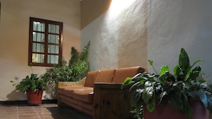 Un espacio interior acogedor con un sofá de cuero marrón, un aparador de madera y varias plantas en macetas.