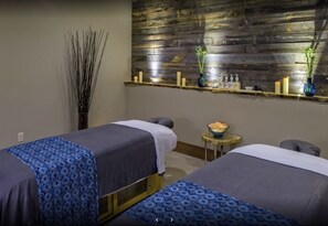 Cozy retreat with two beds, a small table for refreshments, and a shelf for personal items.
