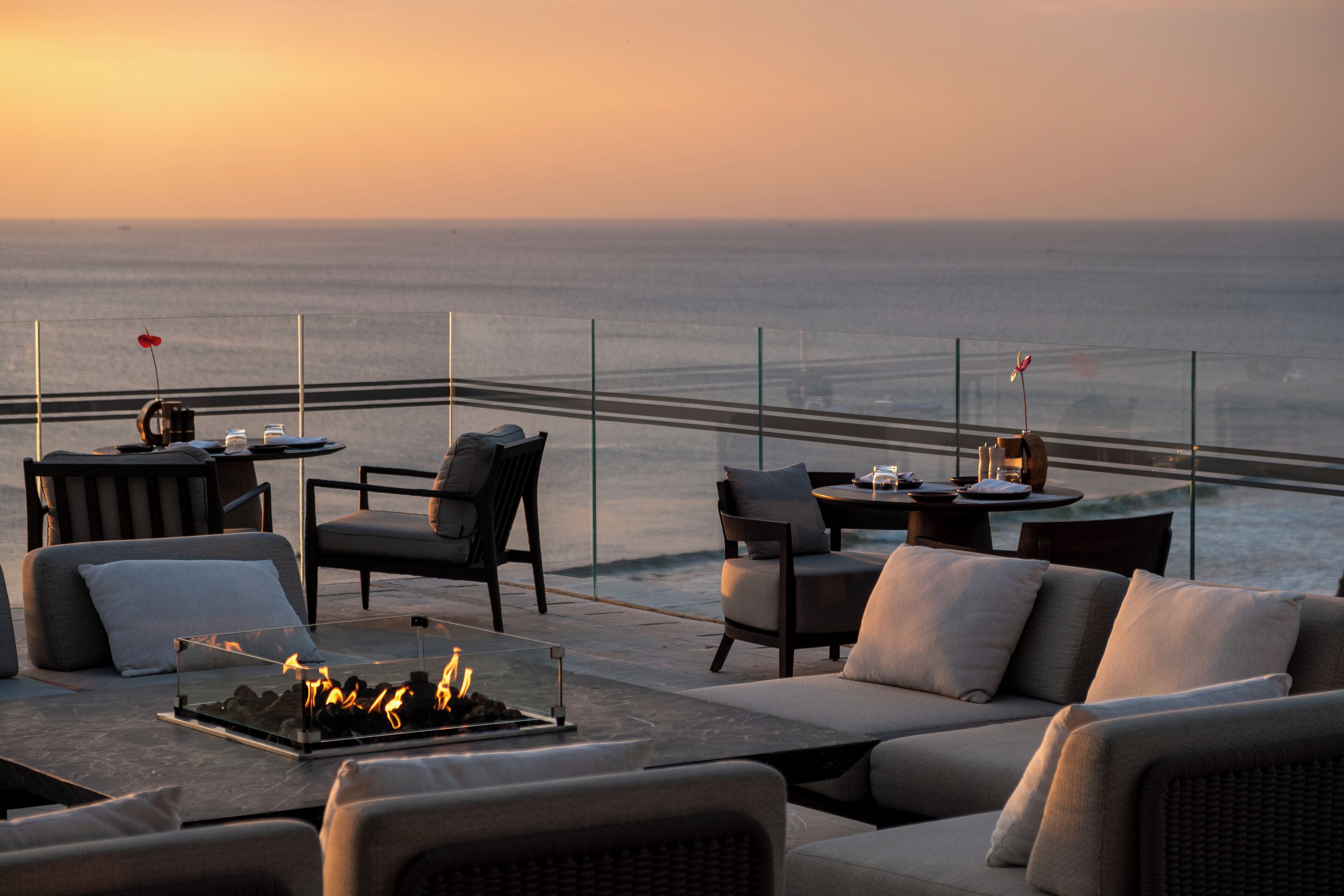 Una terraza en la azotea con mobiliario exterior, una chimenea y vistas al océano.