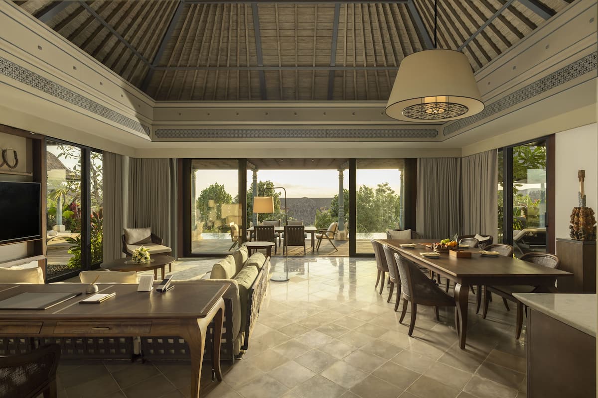 A spacious dining area with a large table, chairs, and a ceiling fan.
