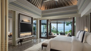 A spacious bedroom with a large bed, a flat-screen TV, and a view of the ocean. - Jumeirah Bali (Pecatu)