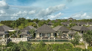 A resort with multiple thatched-roof cottages, a central pool, and lush greenery. - Jumeirah Bali (Pecatu)