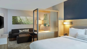 Une chambre d’hôtel avec un lit, un canapé, un bureau et une télévision.