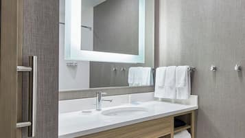 Un baño moderno con un espejo grande, un lavabo blanco y un mueble de tocador de madera.