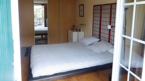 A bedroom with a bed, a bedside table, a lamp, and a sliding door. - "from one Eure to another" A charming house in a garden (SAINTE GEMME MORONVAL)