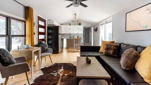 A modern living room with a sofa, a coffee table, and a dining area with a table and chairs. - Lady Bird House ATX walk to Rainey, Cesar Chavez and 6 street (Austin)