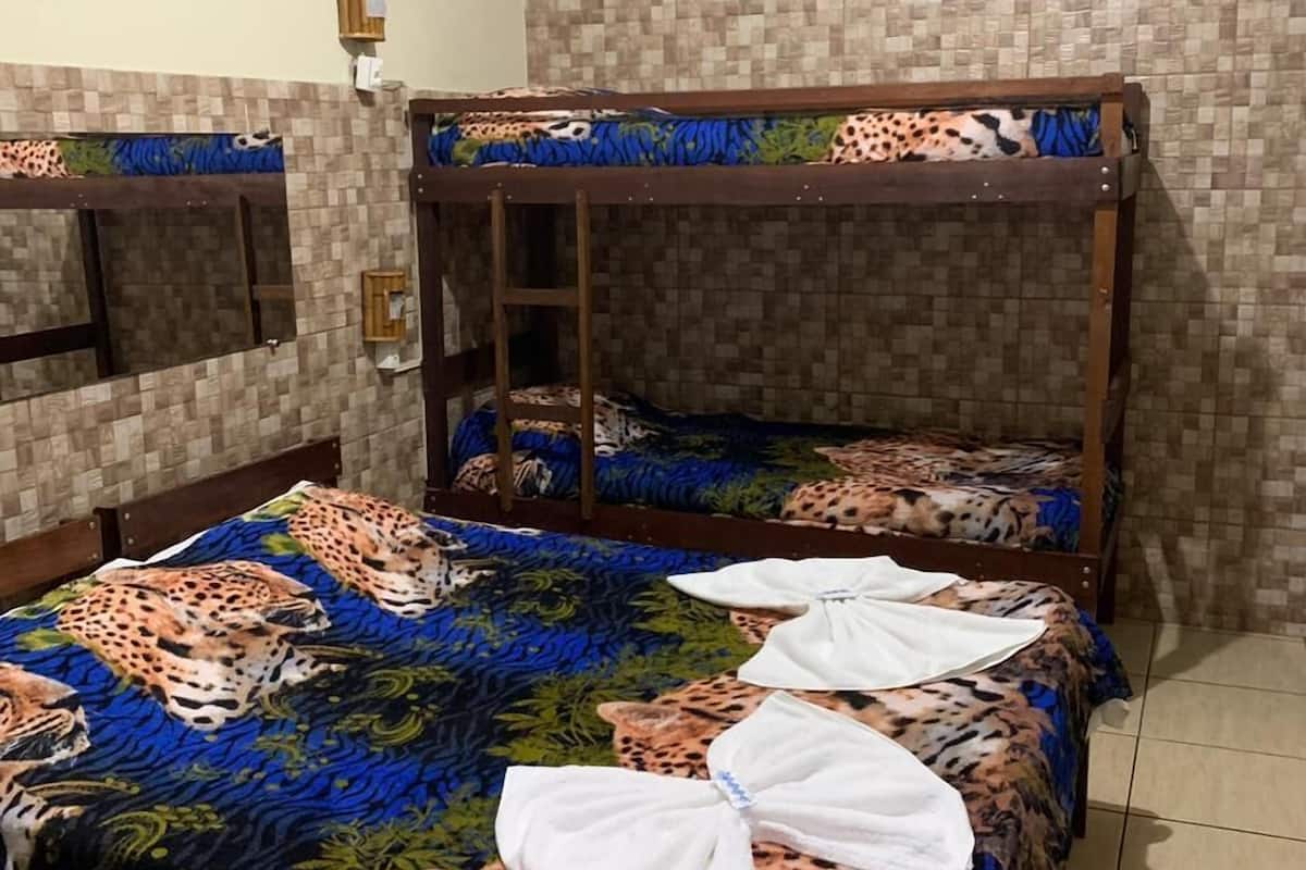 Una habitación con dos literas, cada una con un edredón estampado de leopardo. Una escalera de madera en una litera y un pequeño estante de madera en la pared sobre las camas.