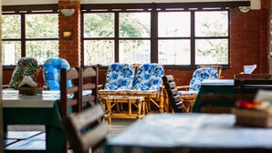 A restaurant with large windows, wicker chairs, and a brick wall. - Pousada Campo Alegre (Itatiaia)