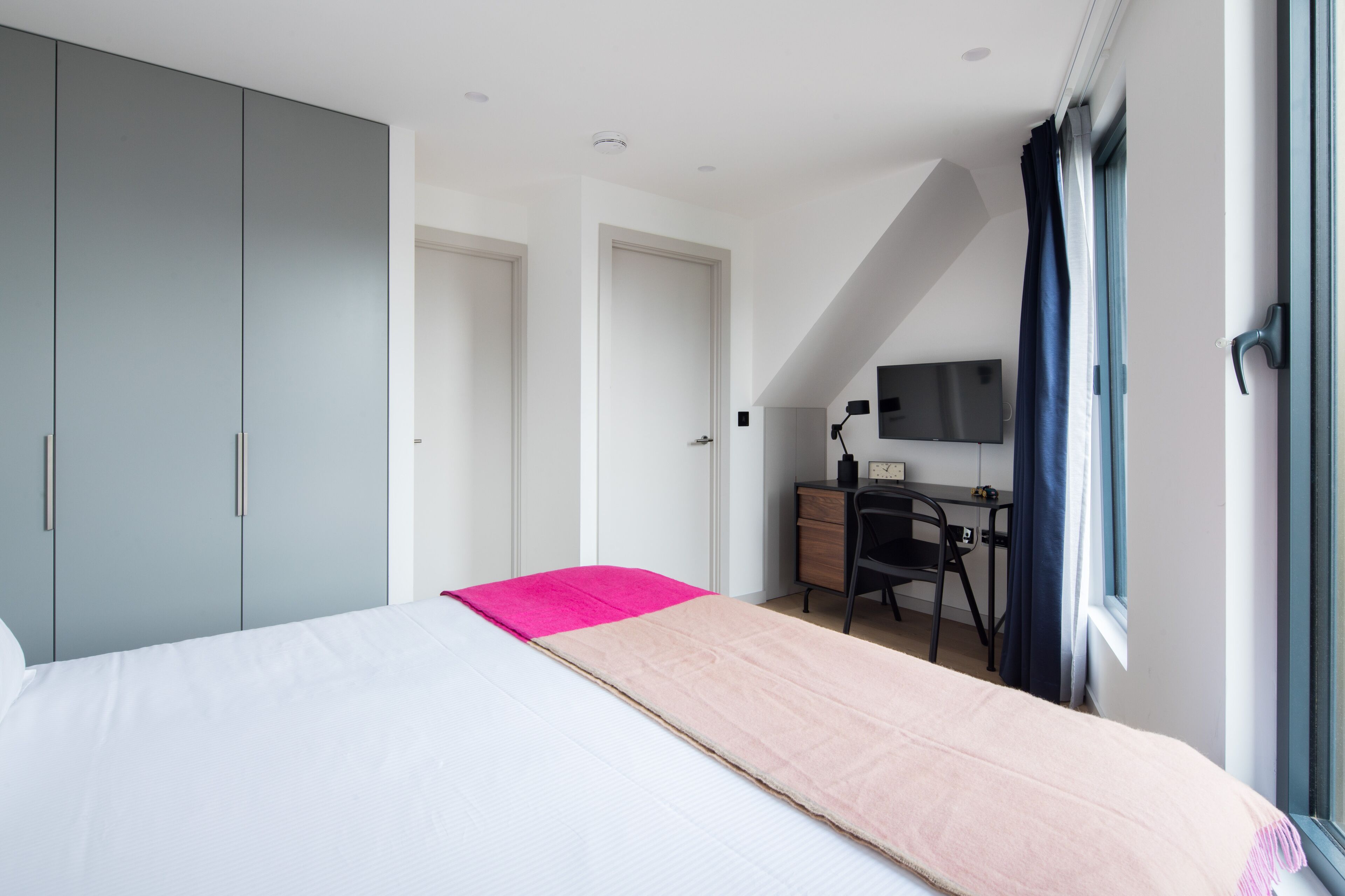 A bedroom with a bed, a desk, a chair, and a wardrobe.
