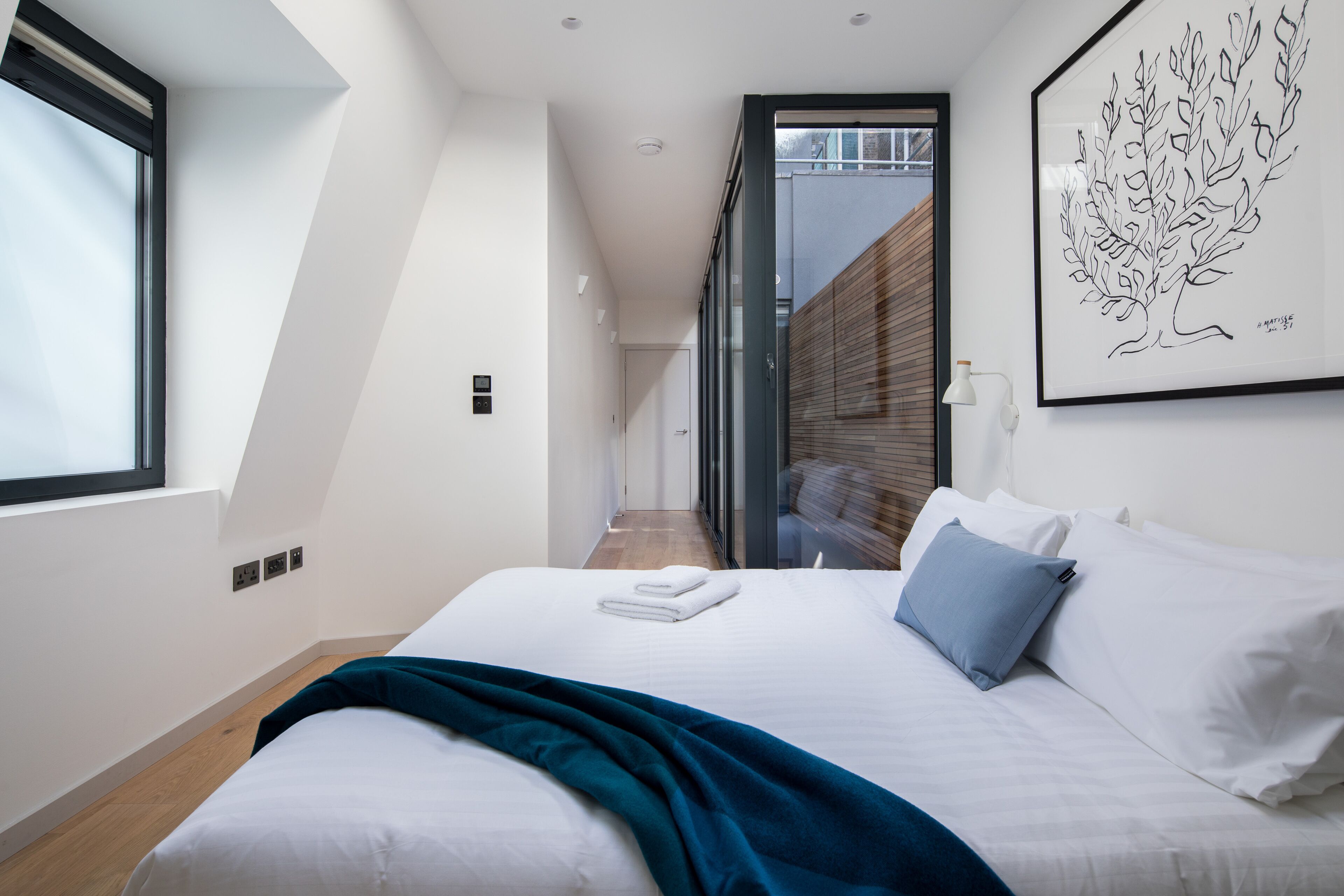Camera moderna con un letto grande, vista su un pontile in legno e un quadro appeso al muro.