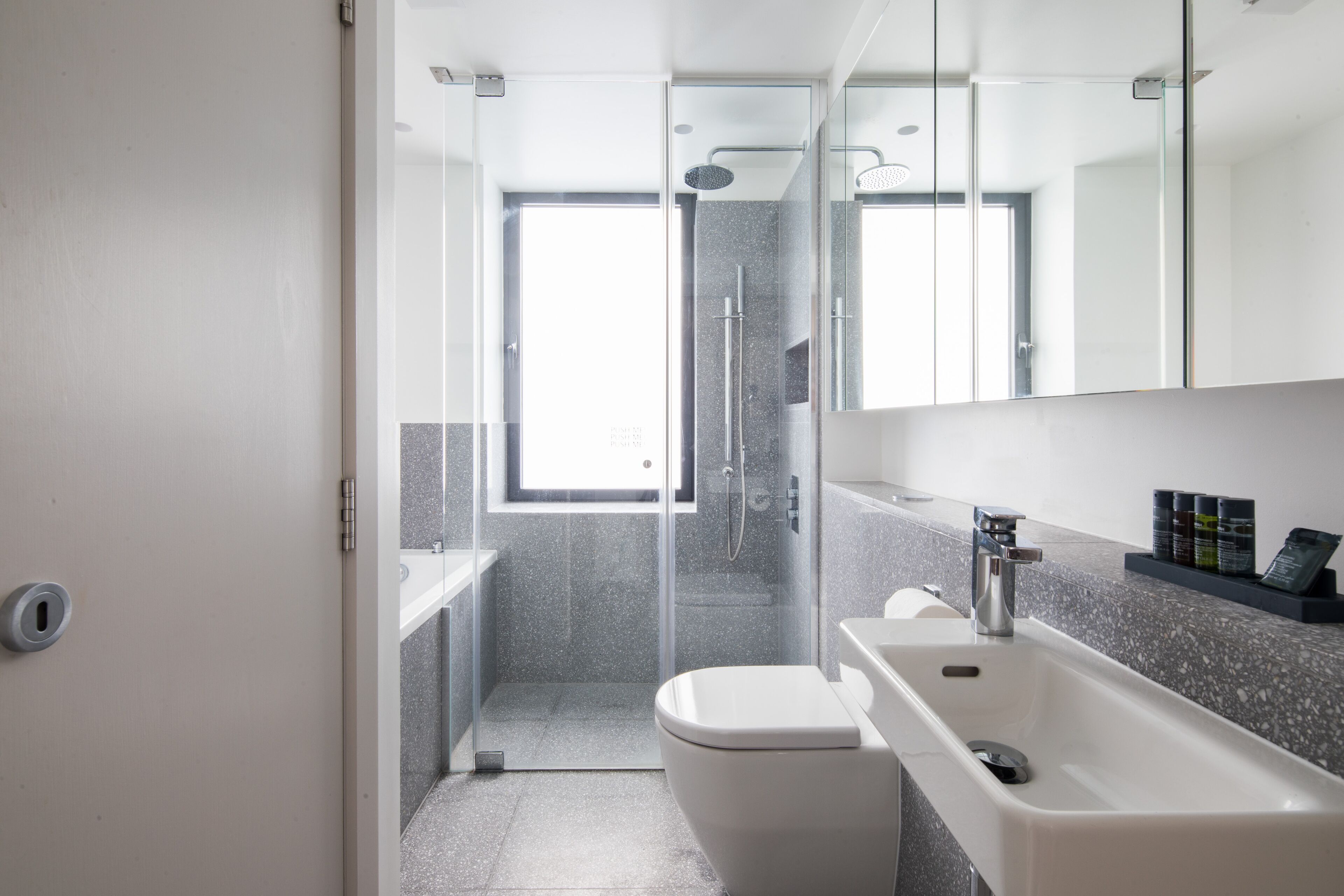Une salle de bain moderne avec une douche à parois de verre, un lavabo blanc et un grand miroir.