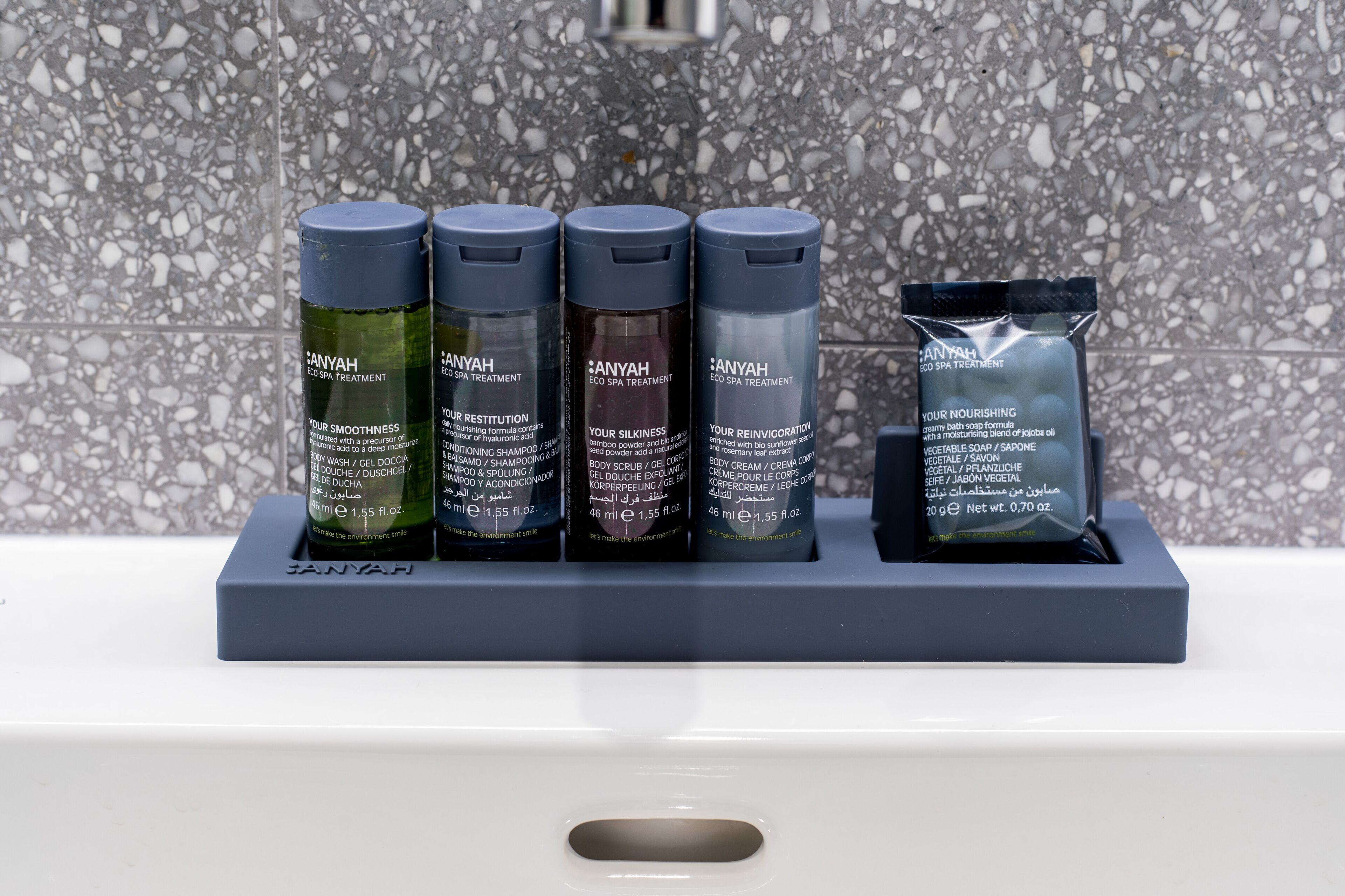 A bathroom sink area with four bottles of Anyah spa treatment products and a packet of body cream.