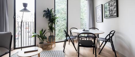 A modern living room with a dining area, large windows, and a view of the city.
