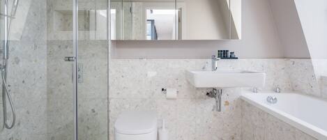 A modern bathroom with a glass-enclosed shower, a white toilet, and a sink with a mirror above.