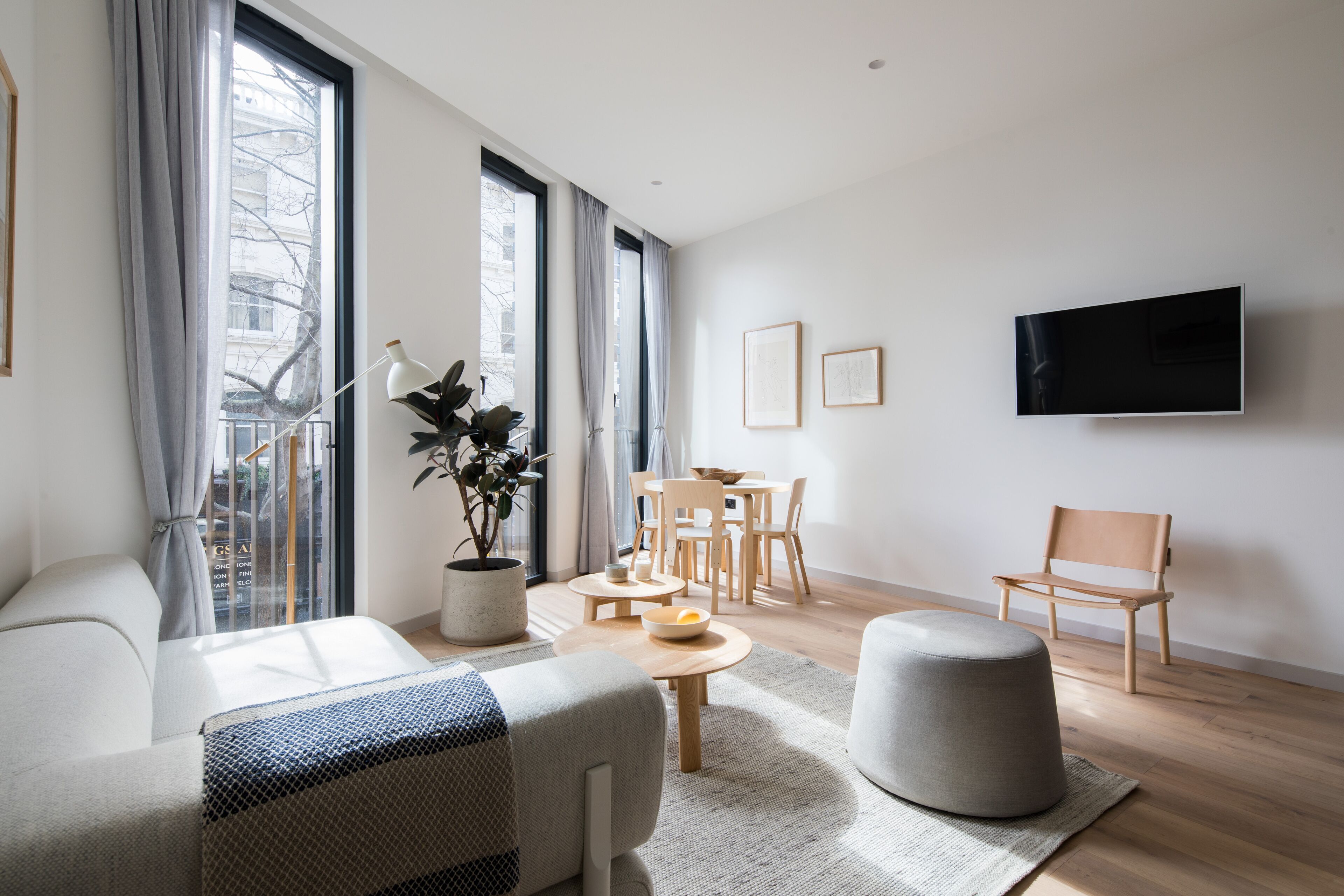 A modern living room with a sofa, ottoman, coffee table, and dining set.