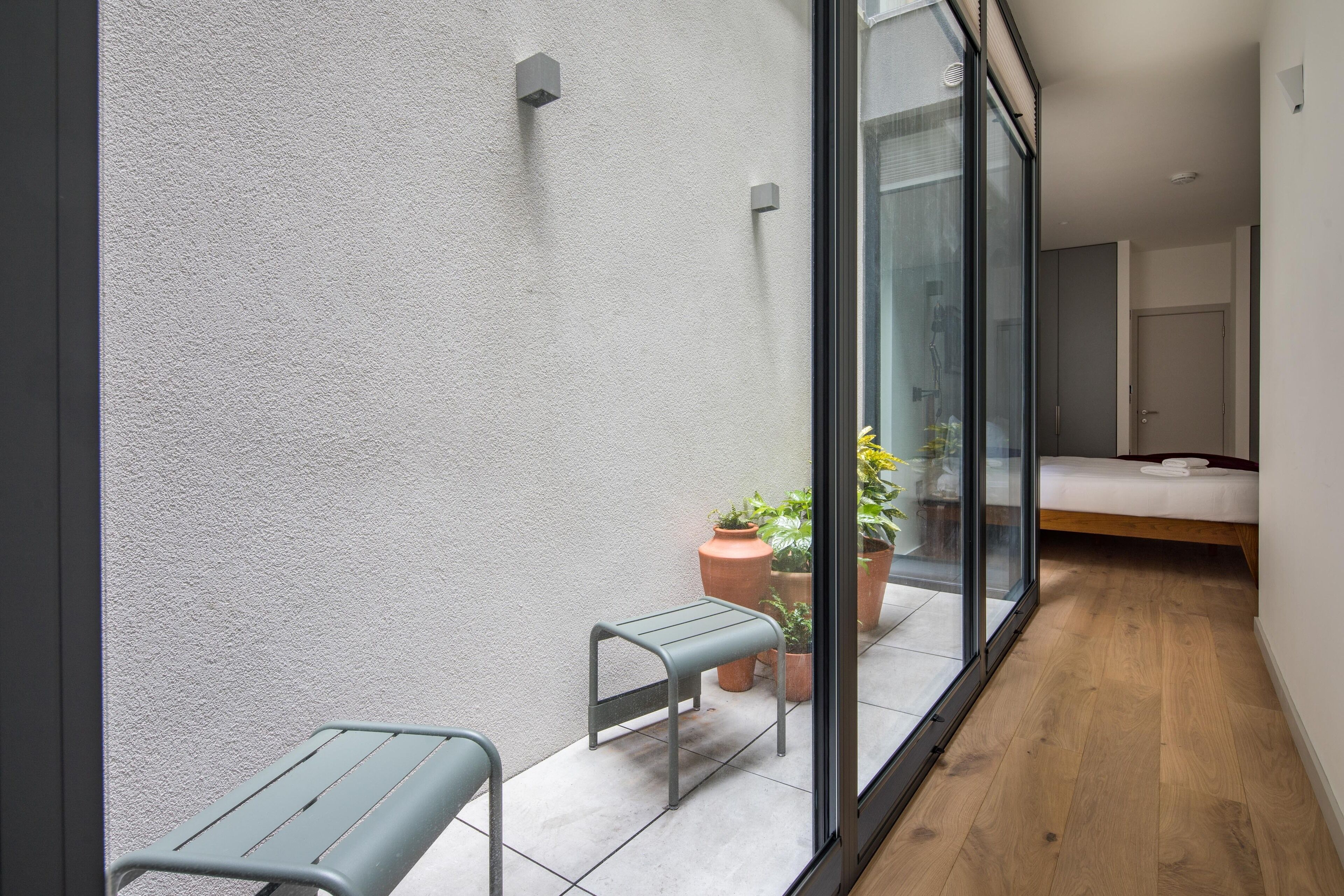 Una habitación moderna con cama, un banco y plantas en macetas.