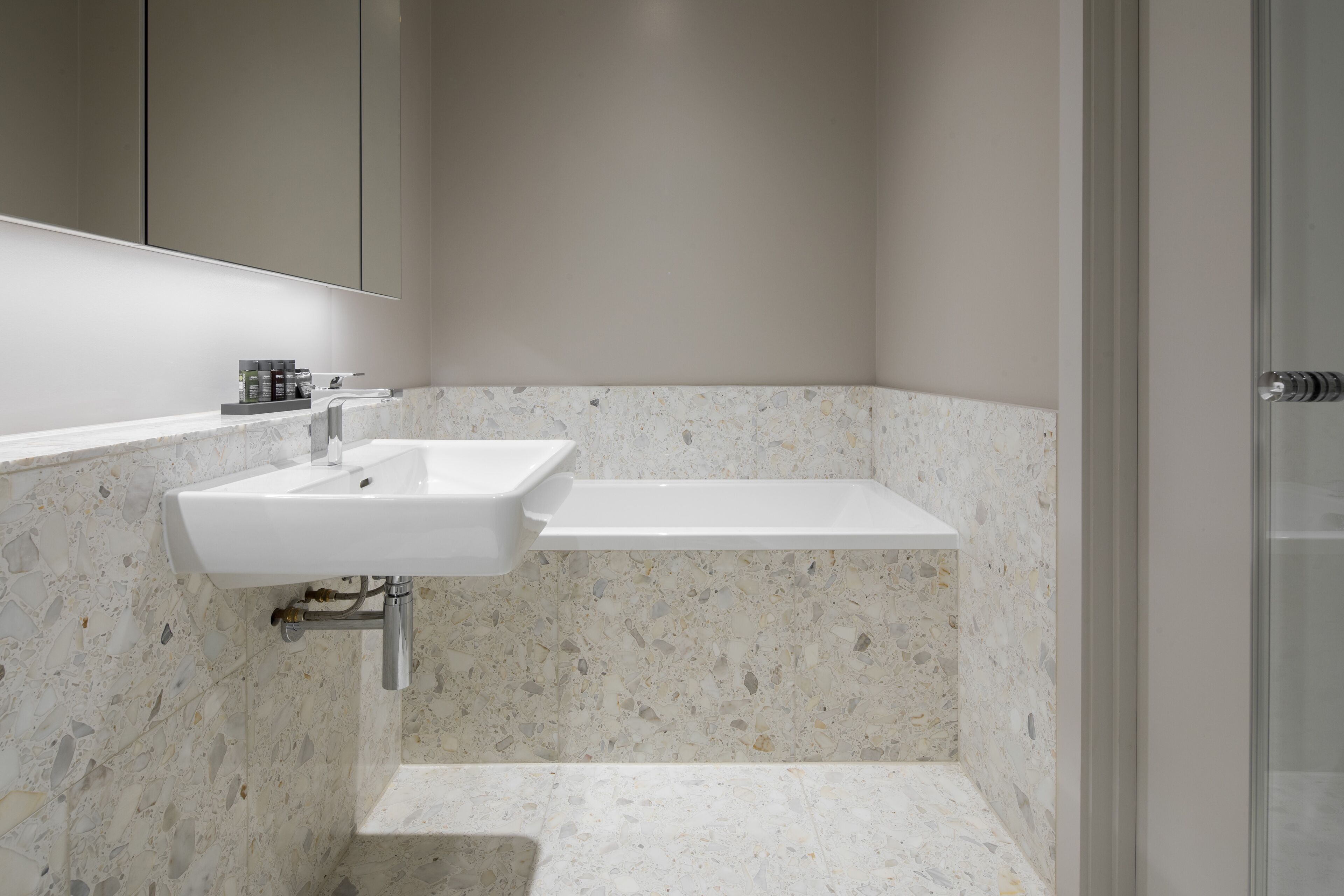 A bathroom with a white sink, a mirror, and a shower area.