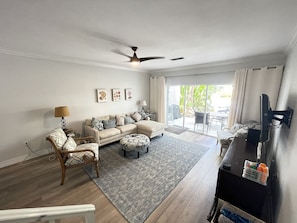 A living room with a sofa, armchairs, a coffee table, a TV, and a ceiling fan.