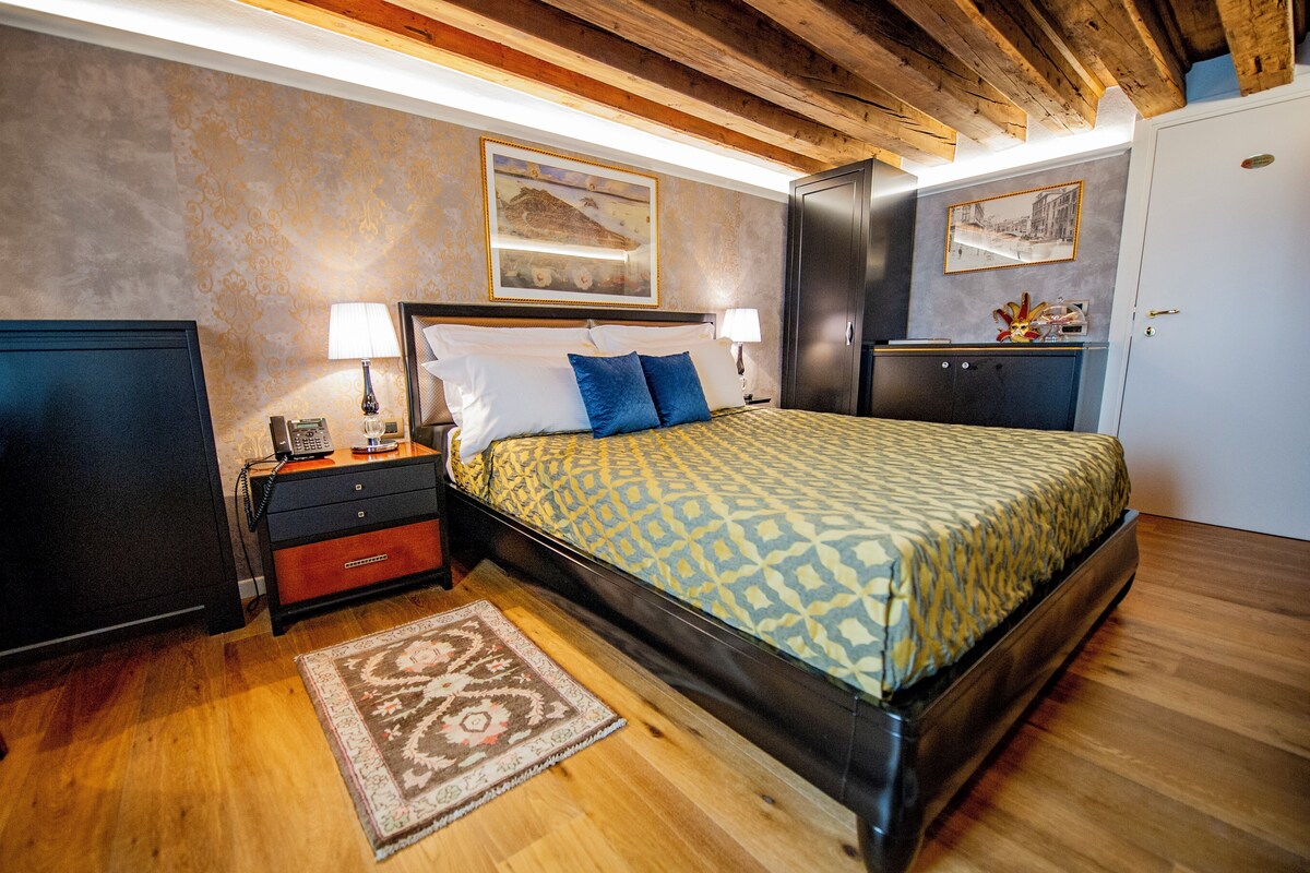 Une chambre à coucher avec un lit, des tables de chevet, un téléphone et une lampe.