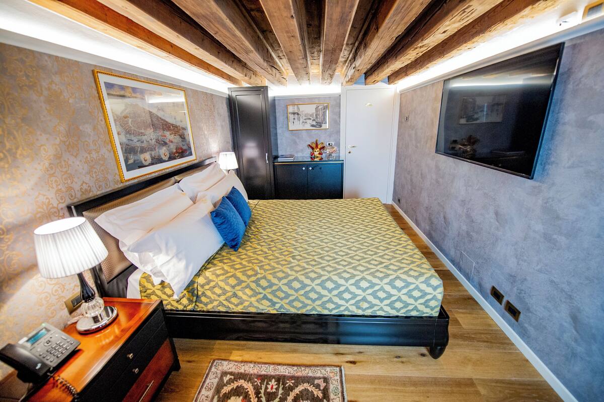 A bedroom with a bed, bedside table, lamp, and a dresser.