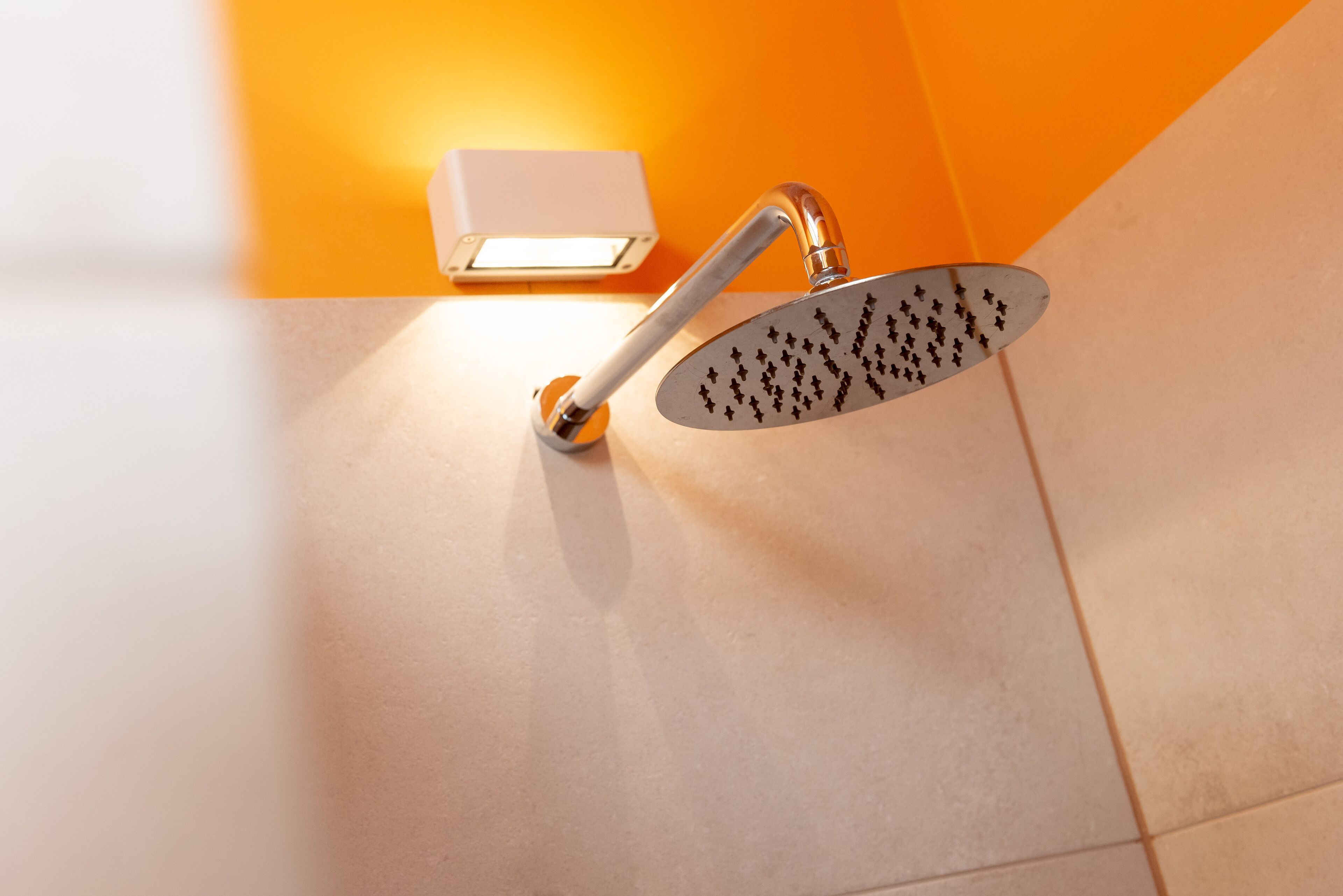 Een douche met een handdouche en een bedieningspaneel aan de muur.