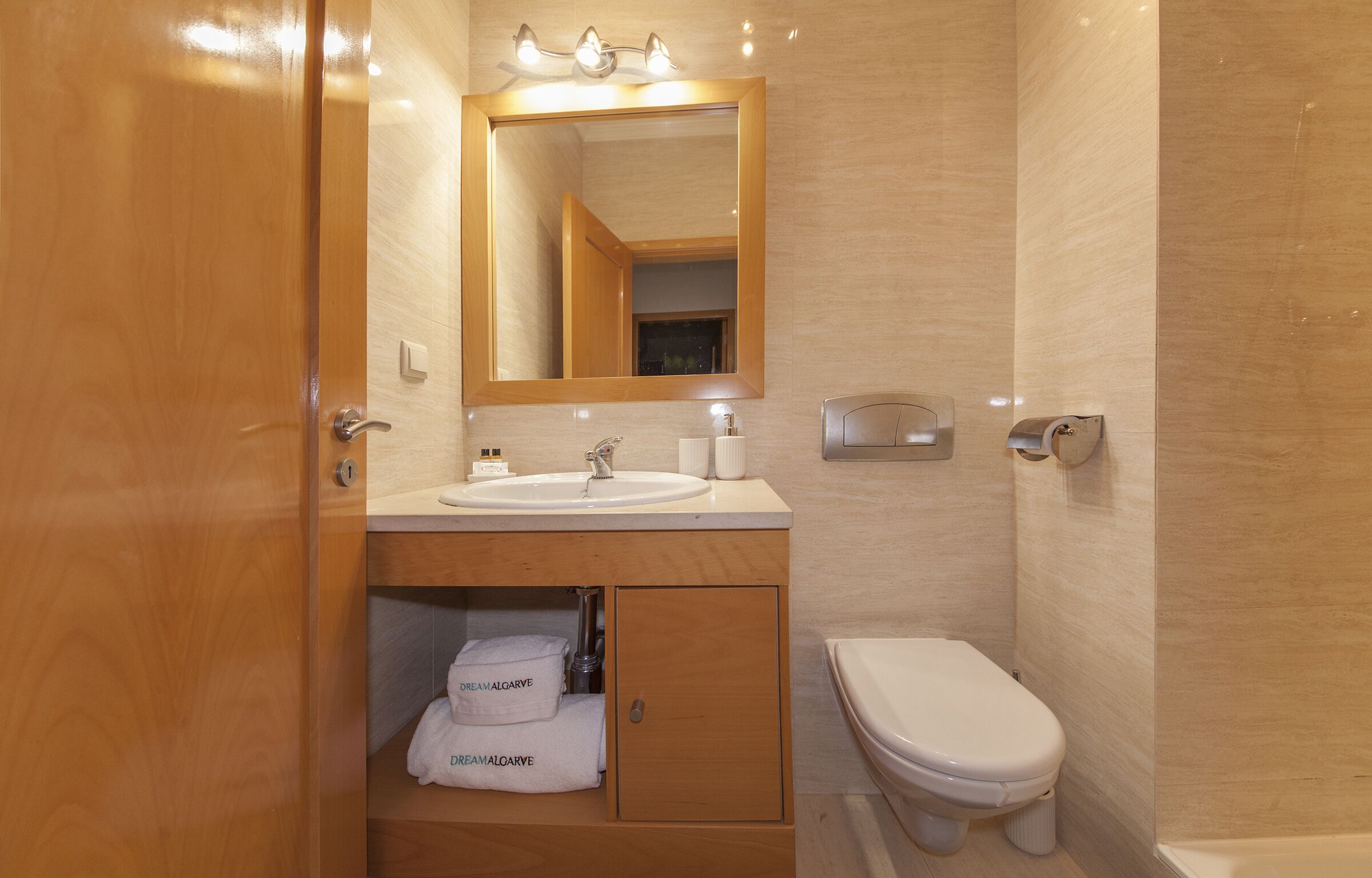Une salle de bain avec un meuble-lavabo en bois, un évier, un miroir et des toilettes.