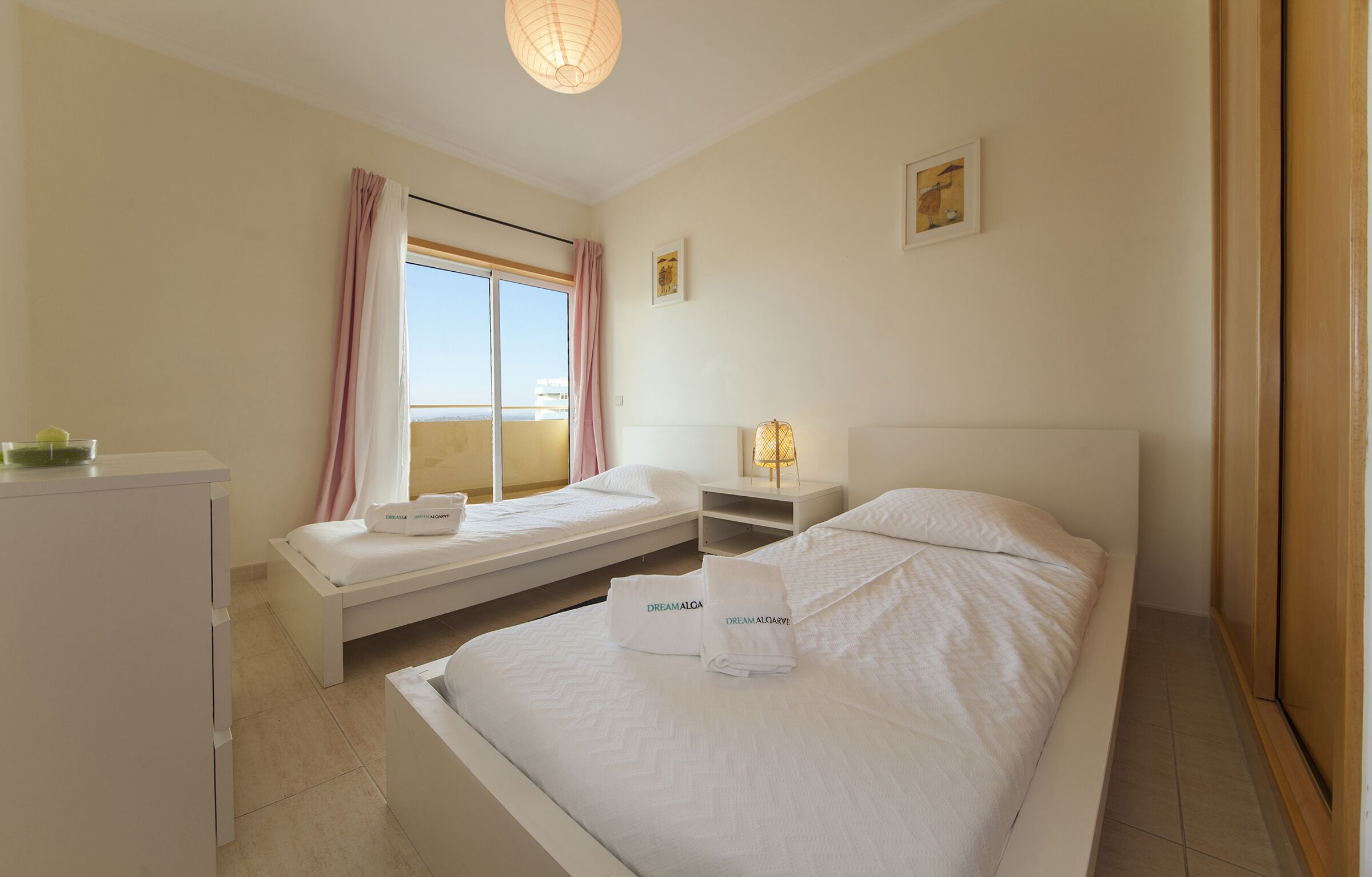 A hotel room with a large bed, a smaller bed, a desk, and a window with a view.