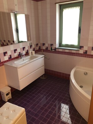 Un baño con lavamanos blanco, espejo y bañera.
