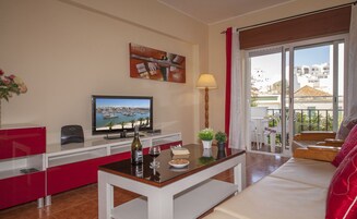 A modern living room with a TV, a bottle of wine, and a table with a bowl of cookies.