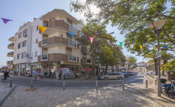 A multi-story building with balconies, a cobblestone street, and a clear sky. - B45 - Main Avenue 2 Bed Apartment (Lagos)