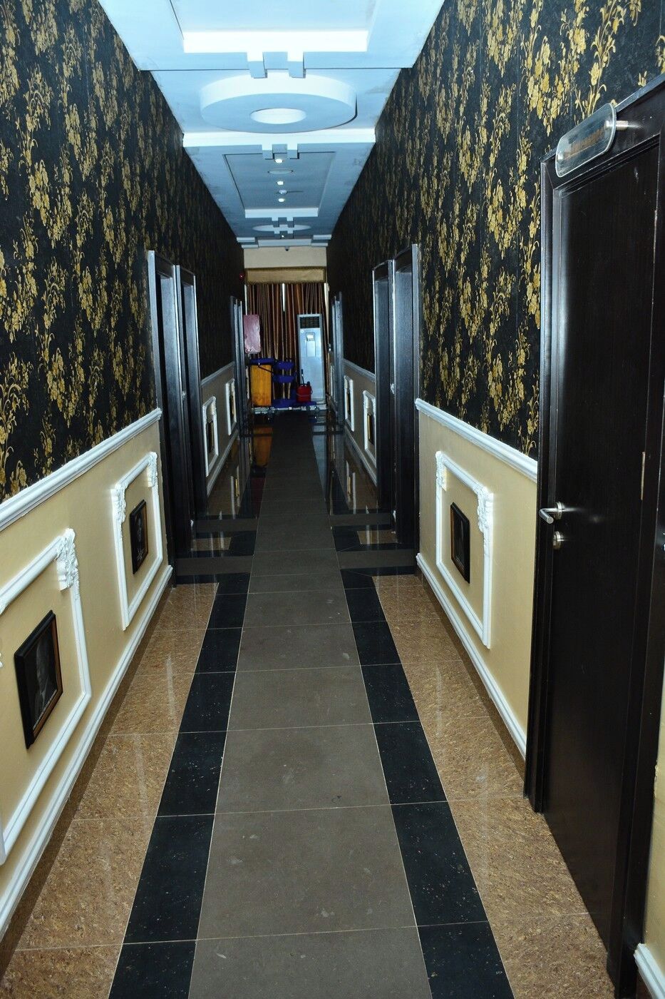 A hallway with patterned wallpaper, a tiled floor, and a door on the right.