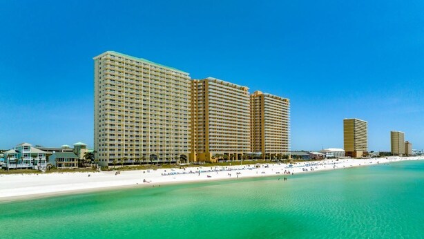 A beachfront hotel with multiple high-rise buildings, a sandy beach, and clear turquoise waters.
