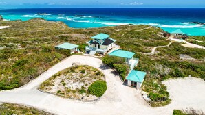 A coastal property with multiple buildings, including a main house and several smaller structures, surrounded by natural vegetation and a clear view of the ocean. - Cottage for 2 at Dragon Cay Resort Mudin Harbour (Mudjin Harbor)