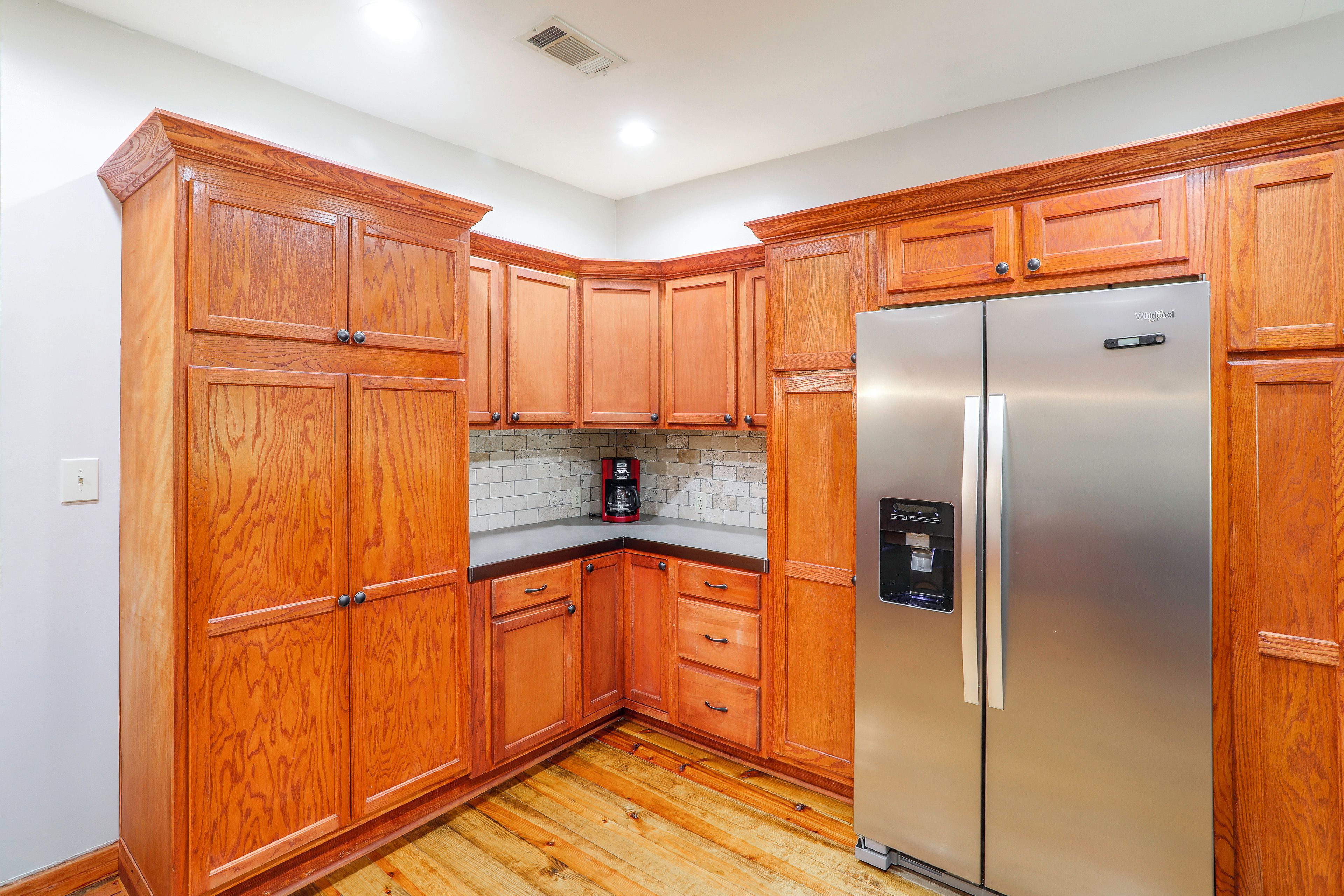 A kitchen with wooden cabinets, a stainless steel refrigerator, and a coffee maker on the countertop.