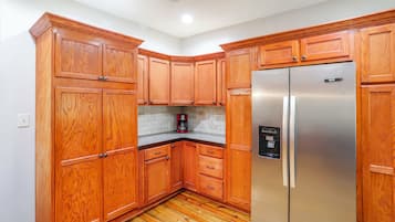 A kitchen with wooden cabinets, a stainless steel refrigerator, and a coffee maker on the countertop.