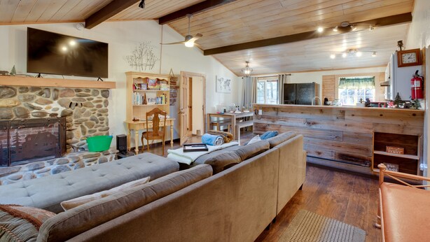 A cozy living room with a stone fireplace, a large sofa, and a wooden ceiling. - 3 Mi to Heavenly Mountain Resort: Home w/ Deck (Stateline)