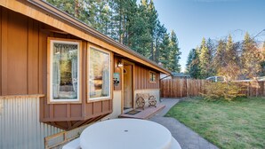 A wooden cabin with a large window, a porch with a bench, and a round table with benches. - 3 Mi to Heavenly Mountain Resort: Home w/ Deck (Stateline)