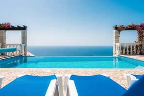 A pool with a clear view of the ocean, surrounded by stone walls and blue lounge chairs. - Blue Sea Villa. Private Heated Pool. Magnificent Ocean view. Quiet. Garden. AC (Faja da Ovelha)